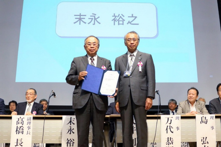 万代恭嗣副会長(会長代行)から理事長の再任が決まった末永裕之氏へ委嘱状が手渡された